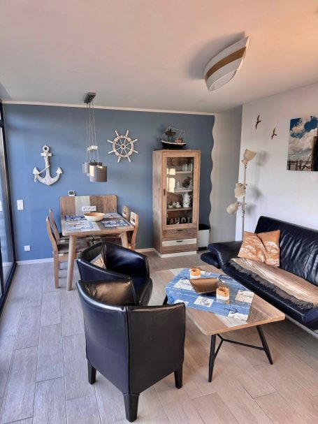 Wohn- und Essbereich Wohn- / Essbereich. Wieder das Doppelsofa und Sessel. Im Hintergrund ein Esstisch, Vier Stühlen, Vitrine mit Gläsern, Maritime Deko.