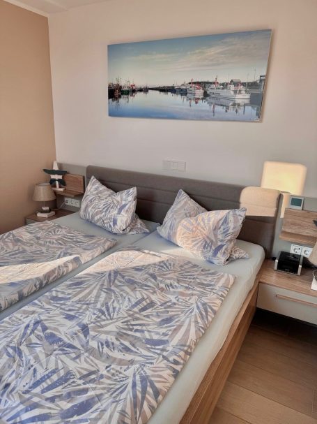 Schlafzimmer I Ein Doppelbett im Schlafzimmer mit Lämpchen auf den Nachttischen auf beiden Seiten. Das Bett ist schön bezogen.